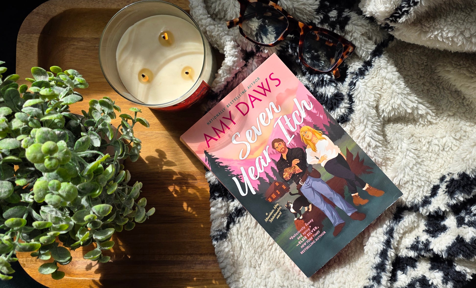 Book titled 'Seven Years High' by Amy Daws on a textured surface with a candle and plant.