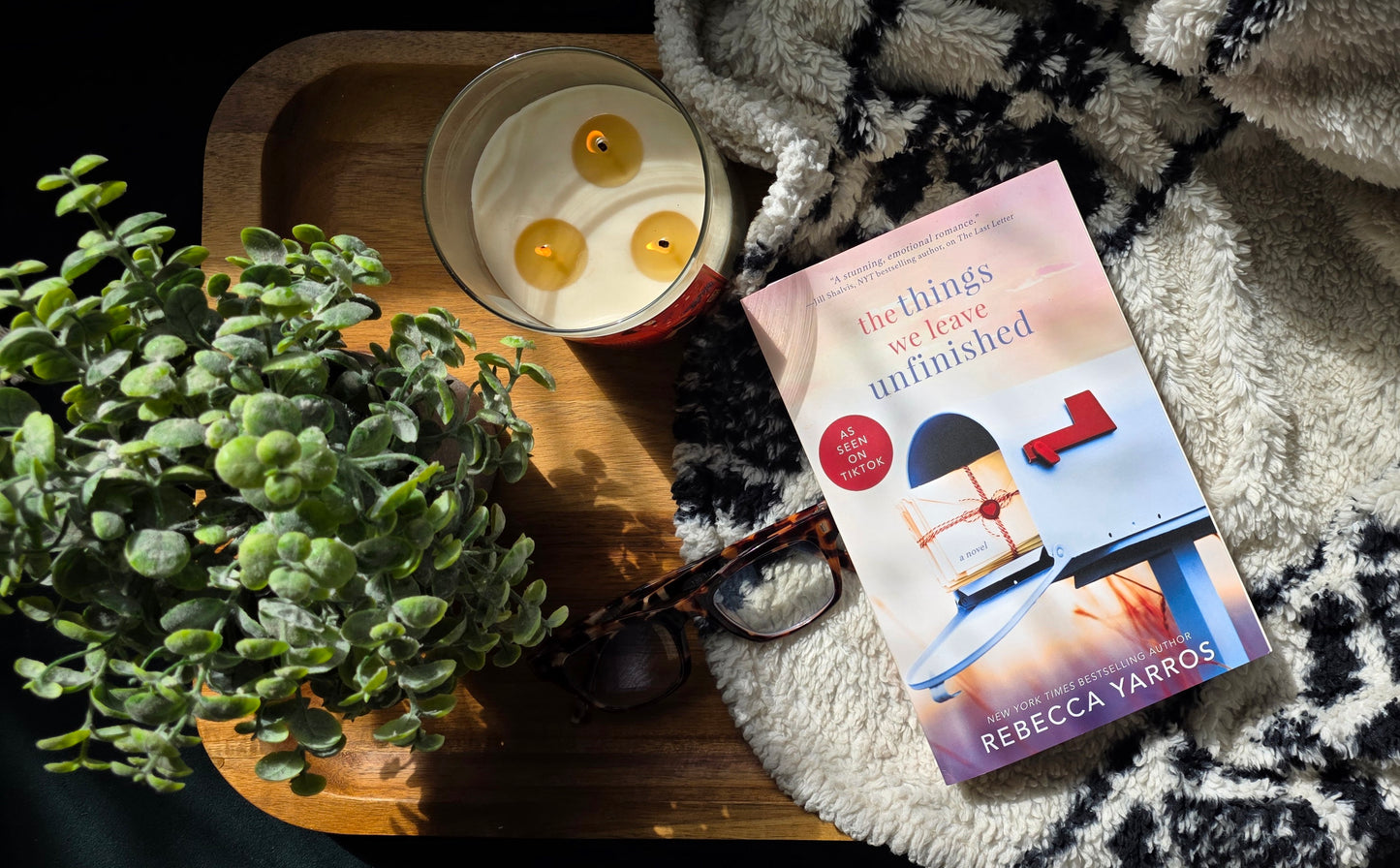 Book titled 'The Wolves Are Amphibious' by Rebecca Yarros on a textured surface with a plant and candle in the background.