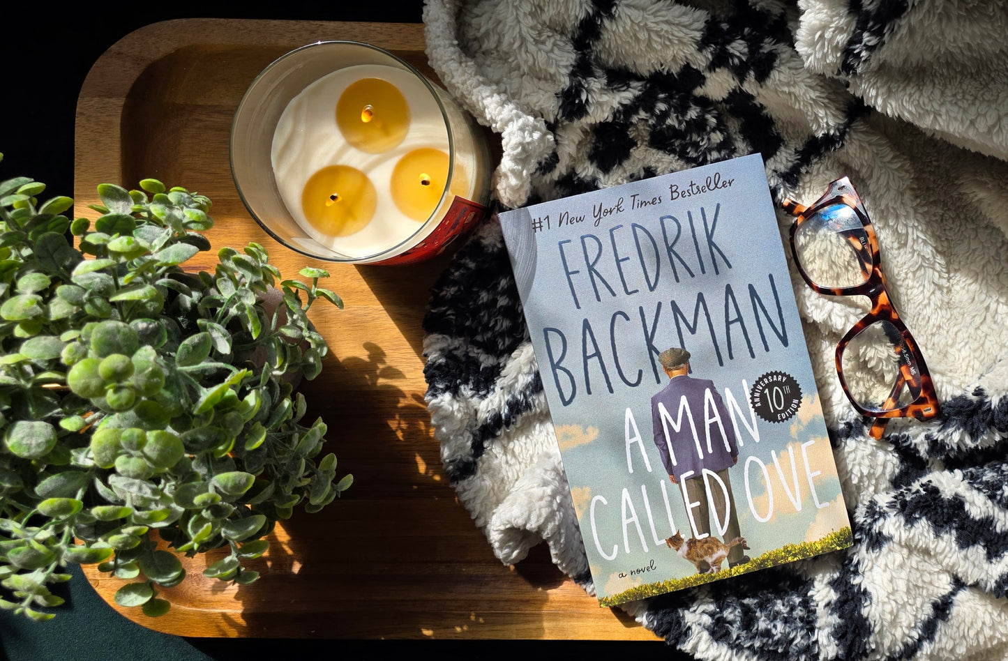 Book 'A Man Called Ove' by Fredrik Backman on a tray with a candle and plant