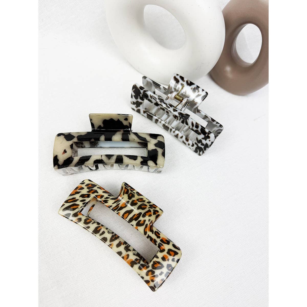 Three hair clips with leopard print design on a white background