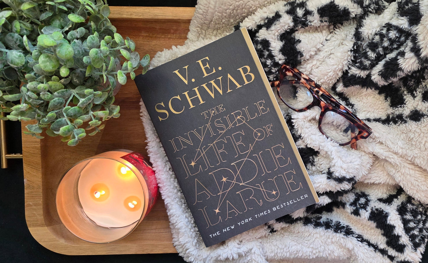 Book on tray with candle, glass, blanket and plant
