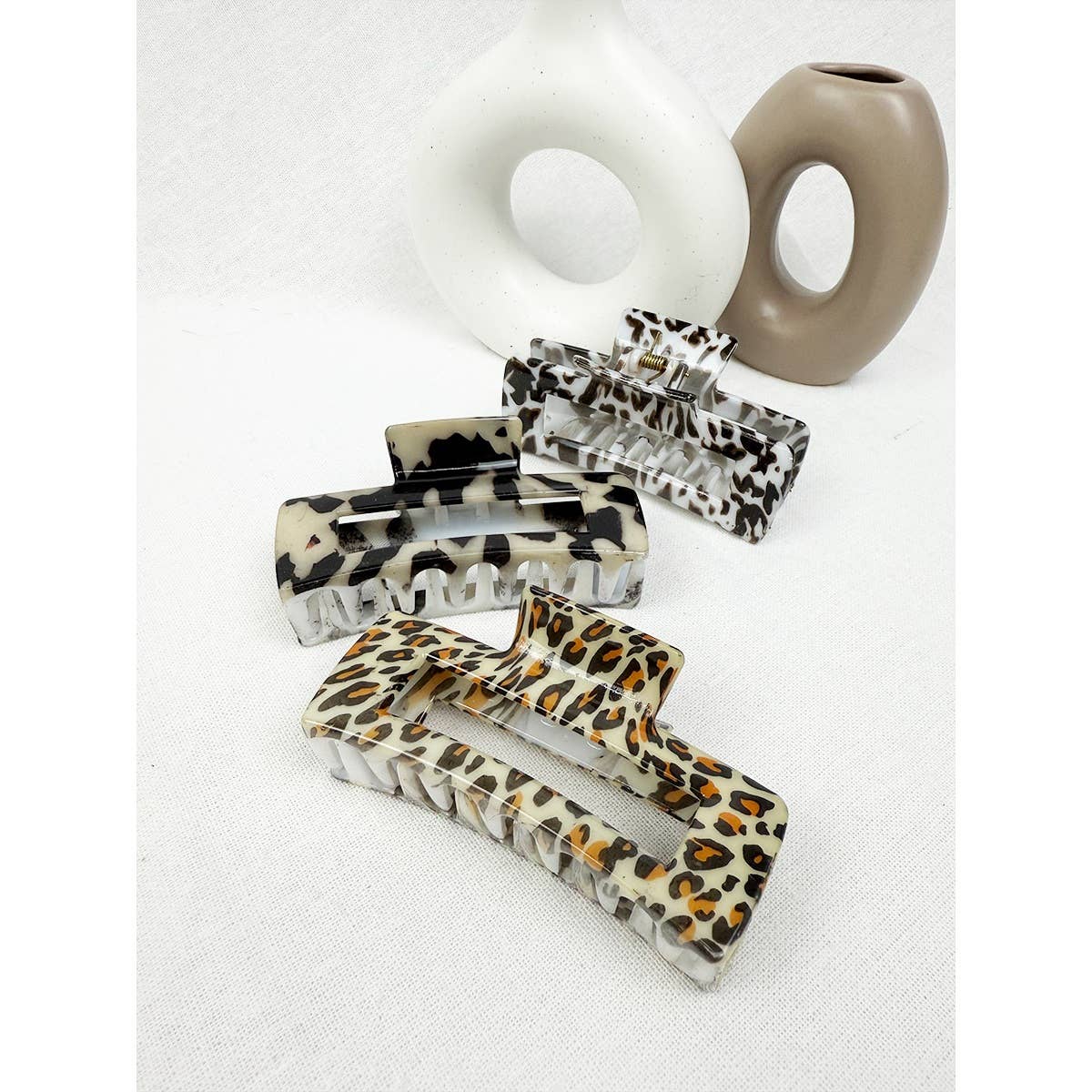 Set of leopard print hair clips on a white background with a beige vase.